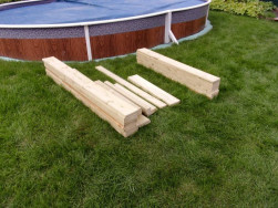 Ohoblovaná prkna pro pískoviště s lavičkami připravena k montáži na zahradě zákaznice.Ohoblovaná prkna pro pískoviště s lavičkami připravena na zahradě zákaznice k montáži.