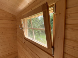 Všechna okna v chatě jsou vyztužena dřevěnými latěmi a jdou otvírat klasicky nebo vyklápěním.