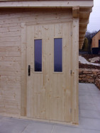 Do dřevěného skladu se vstupuje jednoduchými, částečně prosklenými dveřmi