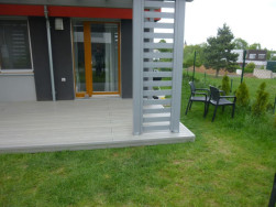 Hotová terasa z kompozitu zastřešená pergolou a doplněna po stranách dvěma atypickými ozdobnými žebříky v šedé barvě