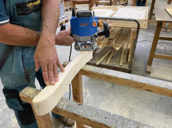 Obroušení dřevěné područky lavice Anglie pomocí elektrické ruční brusky