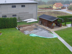 Sauna bude montována vedle dřevěného zahradního domku na nářadí