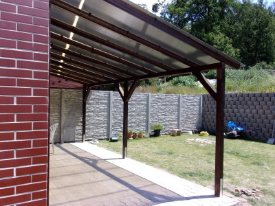 Pergola se zastřešením postavená u zdi domu