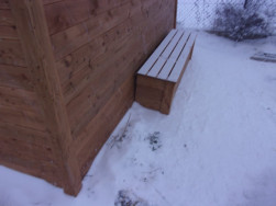 Na boku domku je instalována dřevěná lavička pro zakrytí trubek