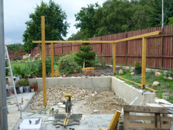 Po vytvrdnutí betonu okolo kovových patek jsme do nich pomocí vratových šroubů připevnili dřevěné stojky pergoly