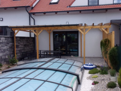 Zastřešená pergola doplněná vysokou dřevěnou zástěnou