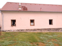 Stará stodola s opravenou omítkou a okny zatím bez dřevěných stříšek