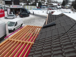 Zastřešení chaty asfaltovým šindelem, nad terasou pouze lamelové zastřešení