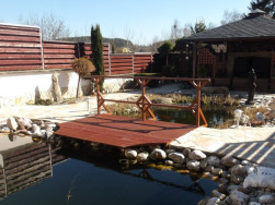 L&aacute;vka z exotick&eacute;ho dřeva přemostila zahradn&iacute; jez&iacute;rko v tom nejuž&scaron;&iacute;m m&iacute;stě