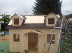 Po olemov&aacute;n&iacute; mansardov&yacute;ch ok&yacute;nek dětsk&eacute;ho domku se asfaltov&yacute;m &scaron;indelem pokryje zbytek střechy