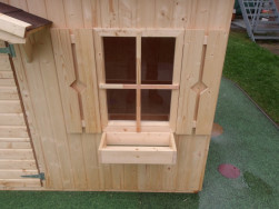 Spodn&iacute; ok&eacute;nka dětsk&eacute;ho domku maj&iacute; po stran&aacute;ch okenice a vpředu dřevěn&yacute; truhl&iacute;k na květiny