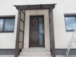 Smrkov&eacute; dřevo použit&eacute; na v&yacute;robu př&iacute;stře&scaron;ku bylo o&scaron;etřeno lazurou v odst&iacute;nu palisandr, lad&iacute; s okny a dveřmi domuDřevěn&eacute;