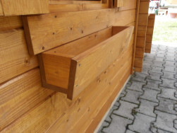 Pod okny dřevěn&eacute;ho domečku je truhl&iacute;k do kter&eacute;ho lze d&aacute; plastov&yacute; truhl&iacute;k třeba s mu&scaron;k&aacute;ty